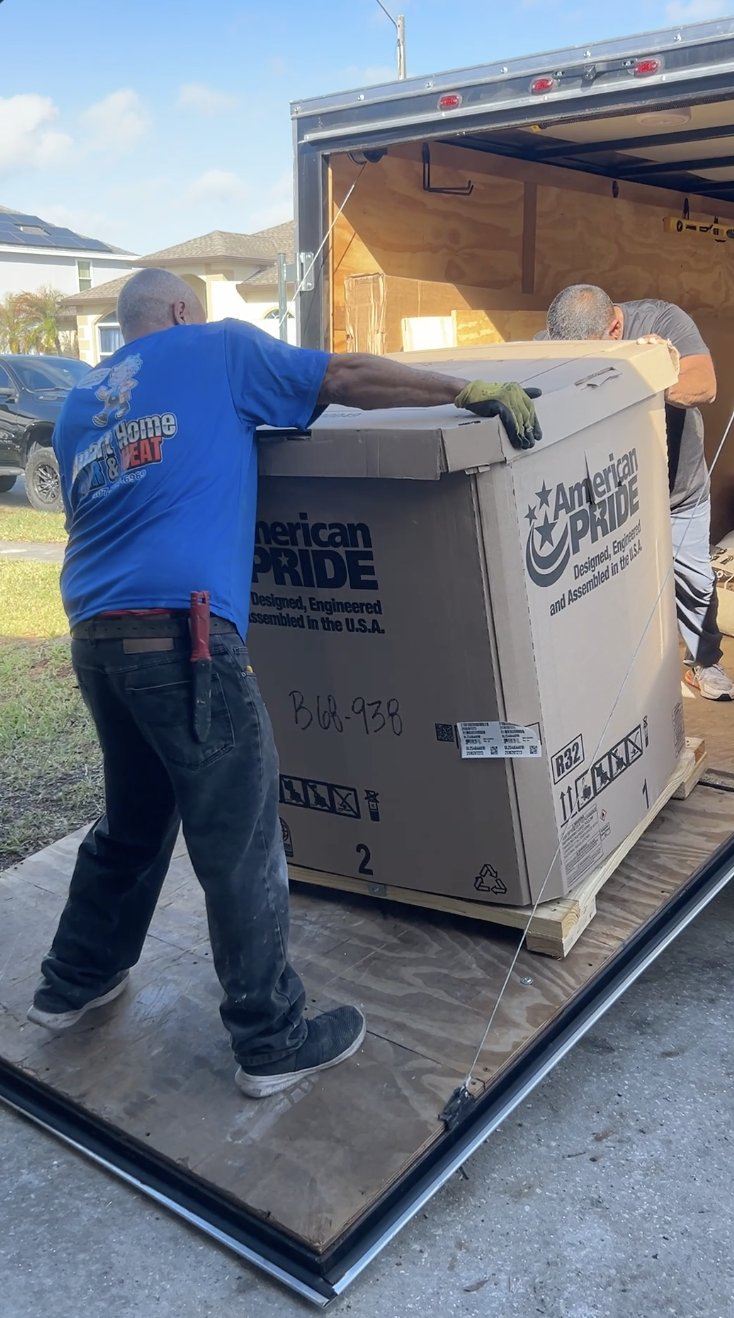 Smart Home Air and Heat team unloading a new condenser unit from the trailer at a job site in East Orlando